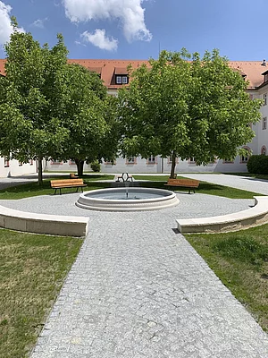 Weg mit Sitzplätzen am gefüllten Brunnen